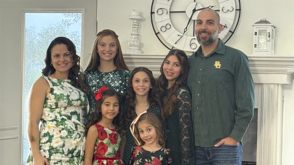Dr. Michael Cerean and his family posed indoors in coordinated green and floral outfits, standing before a large wall clock.